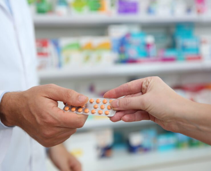 Professional pharmacist giving pills to customer in drugstore, closeup